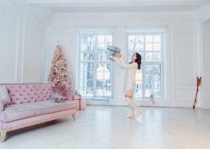 Beautiful young girl with a gift in hand against the window. Christmas concept
